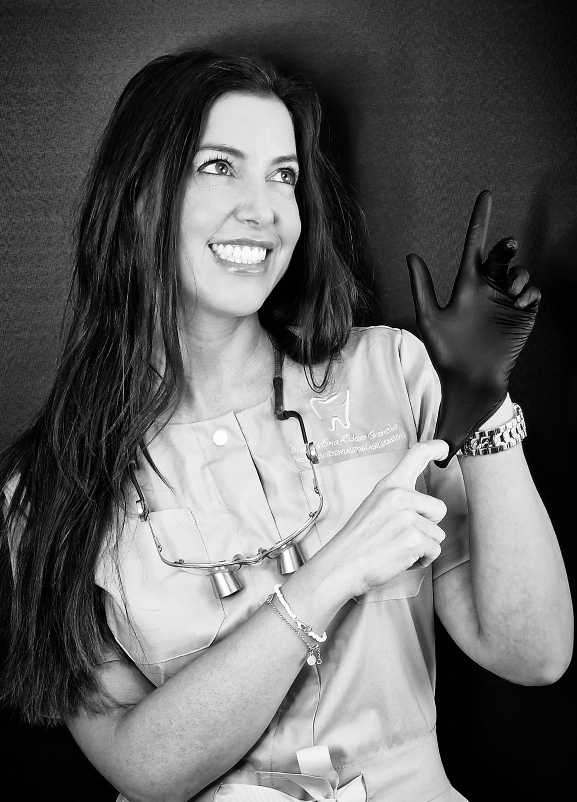 Dra. Catina Ridao García, dentista estética en Málaga, sonriendo con guante negro en blanco y negro